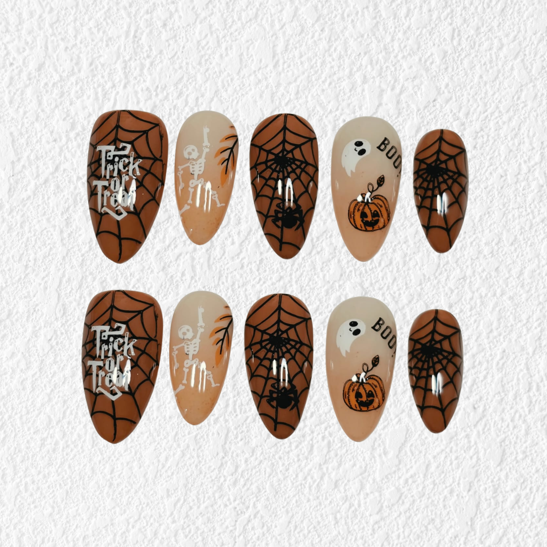 A set of ten Halloween-themed press-on nails arranged in two rows of five on a textured white background. The nails feature brown spiderwebs, black spider legs, white ghosts, orange jack-o'-lanterns, and skeleton designs on beige and dark brown bases.